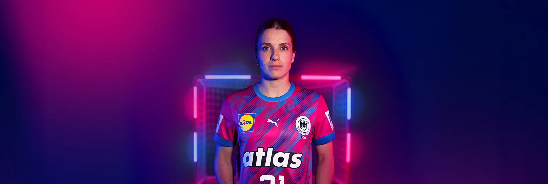 Nationalspielerin Alexia Hauf im magentafarbenen Sondertrikot vor einem mit LED-Stangen beleuchteten Tor.