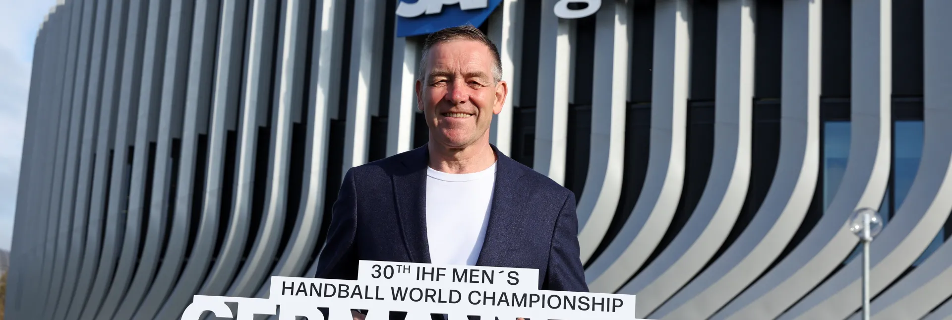 Alfred Gislason mit Schriftzug in der Hand draußen vor den SAP Garden.